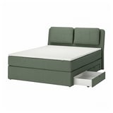 Green upholstered bed with sloped headboard, drawers, and white mattress.
