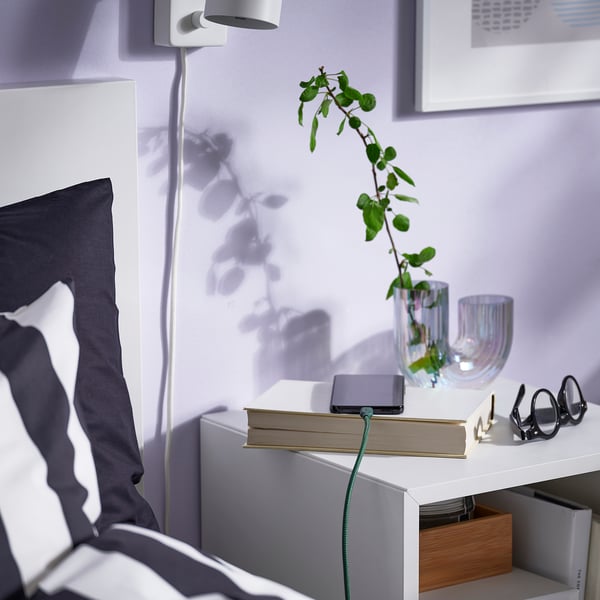 Bedside setup with tablet, plant, and usb cable.