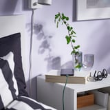 Bedside setup with tablet, plant, and usb cable.