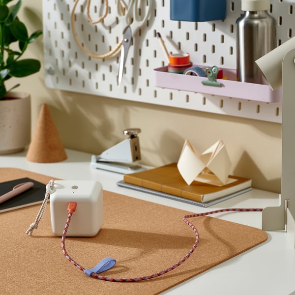 A colorful, coiled usb-c cable rests on a cork mat, surrounded by home office supplies and storage solutions.