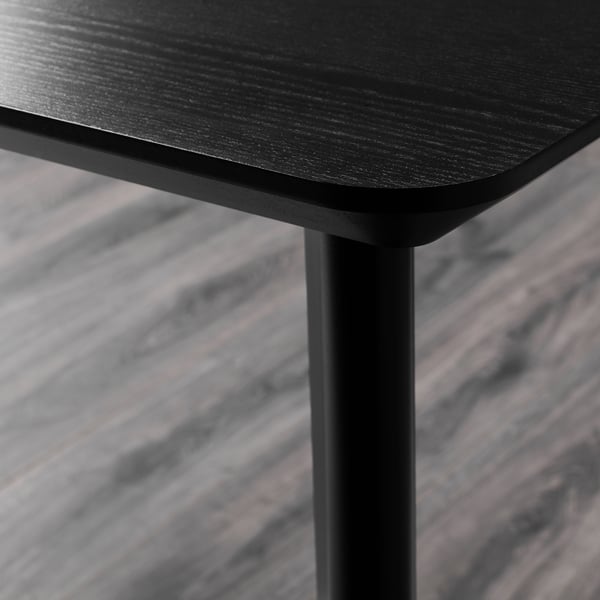 A close-up of a sleek black table edge, showcasing smooth, high-quality wood and sturdy metal legs.