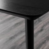 A close-up of a sleek black table edge, showcasing smooth, high-quality wood and sturdy metal legs.