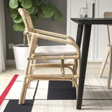 Wicker chair with light gray cushion beside table. Modern design, suitable for indoor dining.