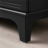Black modern cabinet with sleek handles and sturdy legs on a light wooden floor. Shows quality design and finish.