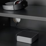 On sleek black desk, white headphones lay atop, connected to small speaker, tech setup arranged neatly.