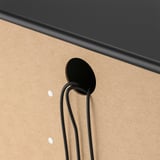 Black minimalist wall-mounted coat hook on beige wall; sleek, sturdy design.