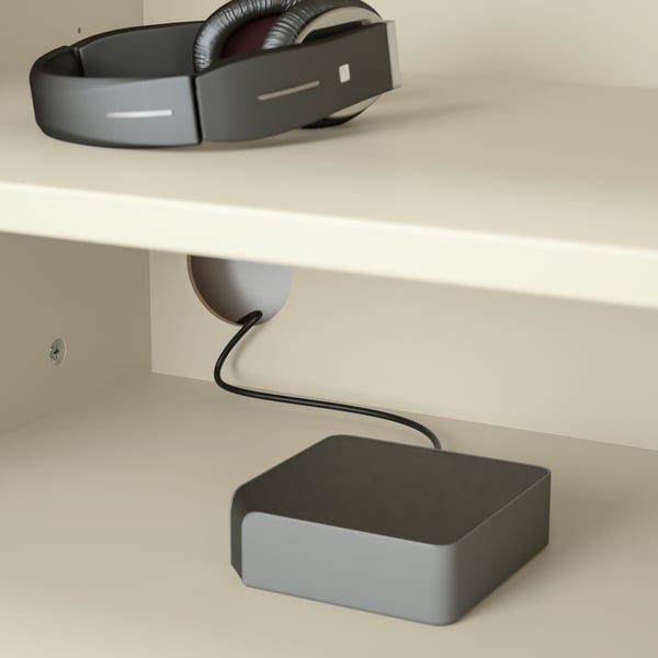 A white desk with a headset, cable management, and charging device.