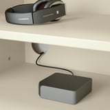 A white desk with a headset, cable management, and charging device.