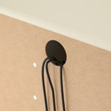 Black cable management clip on beige wall, organizing cords.
