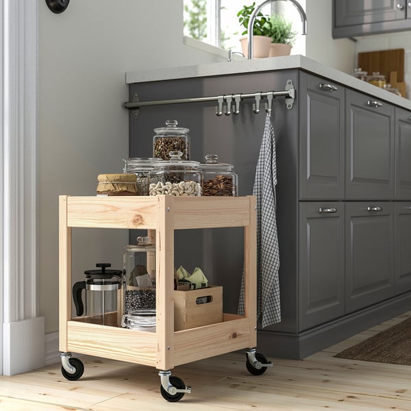Wooden LOSHULT trolley with clear jars and castors. Small, mobile, fits kitchen corners. Made of natural pine, light brown.