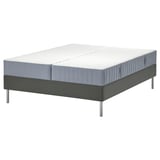 Flat-pack gray bed base with divided mattress, featuring pocket springs and comfort zones.