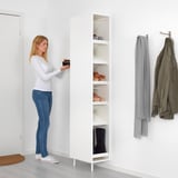 A person organizing shoes on a MACKAPÄR shoe cabinet with open shelves, holding about 12 pairs, fixed to the wall.