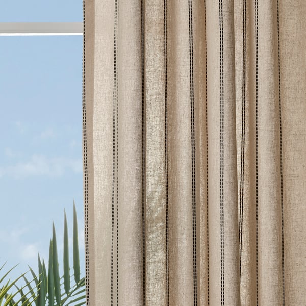 Beige striped curtains near a window with soft light and plant leaves.