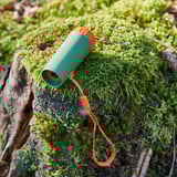 Mossy log with green telescope, orange strap. Nature exploration toy. Durable, colorful.