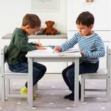 Two boys sit at a white MÅLA table drawing with colorful pencils. Cada niño usa lápices de colores.