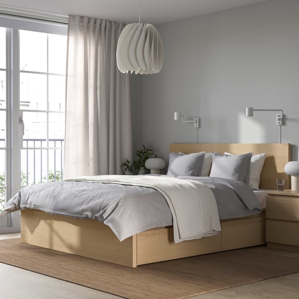 Modern bedroom with MALM light oak bed, gray curtains, plant, and lamp.