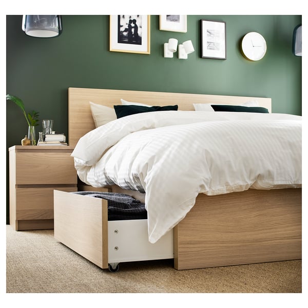 Modern bedroom with green walls featuring a light wood MALM bed with four storage drawers, white bedding, and decorative items.