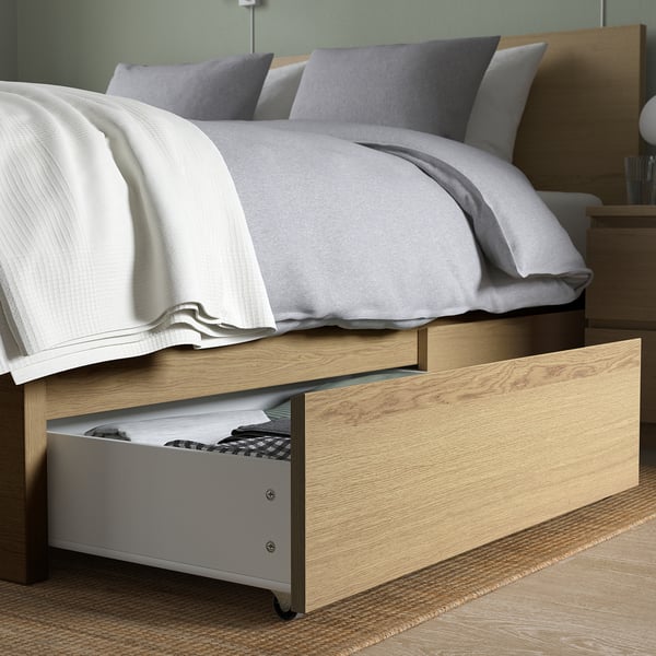 Bed with open storage drawer under white blanket.