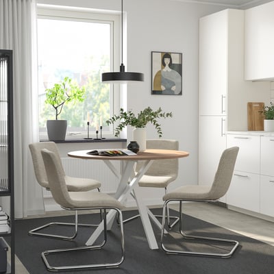 Modern dining area with round table, grey chairs, and big windows.