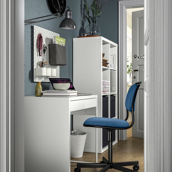 Home office setup with white micke desk, blue örfjäll chair, and kallax shelf, neatly organized.