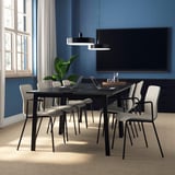 Modern conference room with black table, grey chairs, flat-screen tv, and plant.