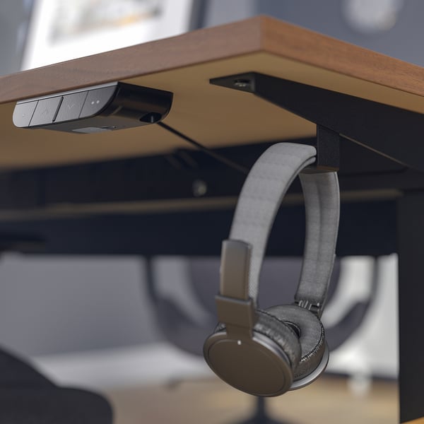 Desk with motorized height control; headphones hang on side hook.