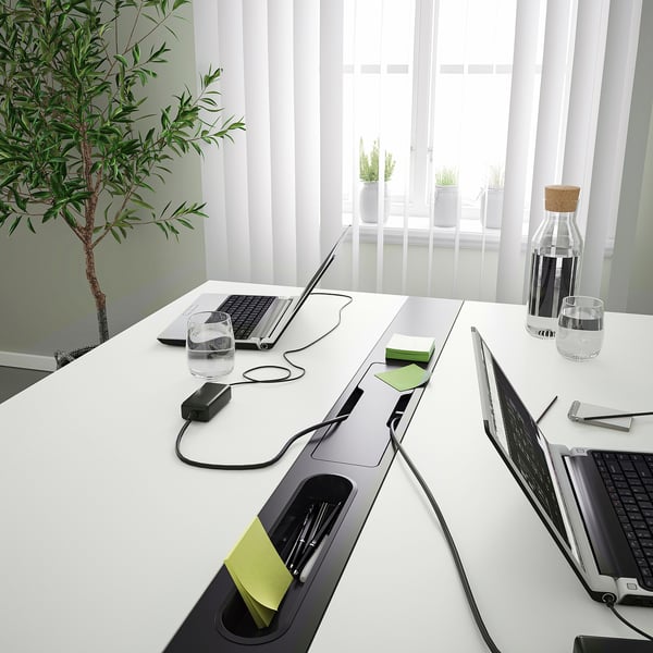 Modern conference table with power outlets and usb ports for charging devices, designed for collaboration with built-in slots for notepads and pens.