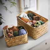 Two bamboo baskets on a shelf store yarn, knitting accessories, and small toys, showcasing organized craft storage.