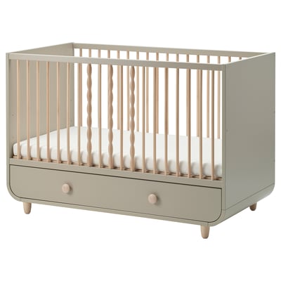 Modern beige MYLLRA crib with wooden spindles, adjustable height, and a storage drawer.