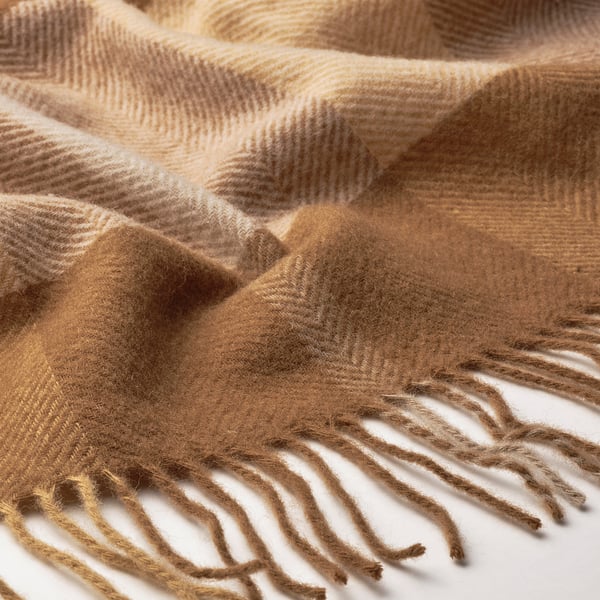 Beautifully woven wool throw with soft, cozy texture and fringe, light brown color.