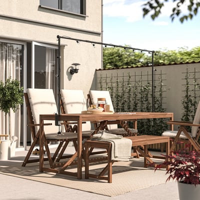 Backyard patio with dark wood NÄMMARÖ dining set and hanging lights. Comfortable for outdoor meals and relaxation.