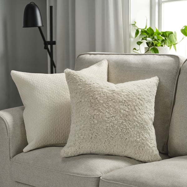 Two NÄTNÄVA pillows on gray couch, soft & textured. With lamp & plant for cozy style.