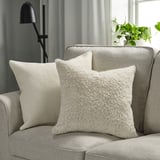 Two NÄTNÄVA pillows on gray couch, soft & textured. With lamp & plant for cozy style.