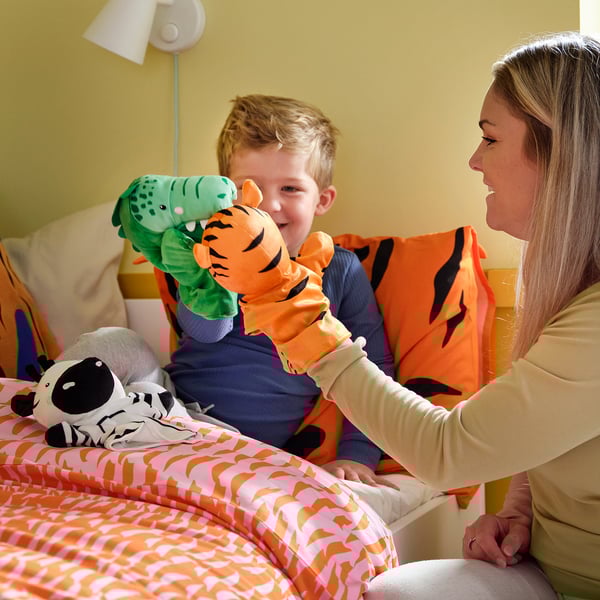 Woman & child play with puppets on orange bed.