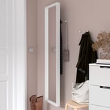 A mirrored cabinet on a pink wall with coat hook. Underneath, a stool holds a bag and boots, next to a drawer with books and dried flowers.