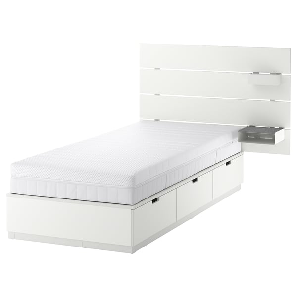 Depicts a white NORDLI bed frame with three drawers and a wall-mounted headboard featuring a box and shelf.