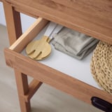 Wooden drawer with gray cloth, woven coaster, and bamboo organizer under table.