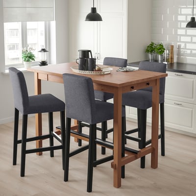 Small modern wood bar set with four grey cushioned stools beside a kitchen window.