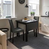 Small modern black NORDVIKEN drop-leaf table and chairs by window, perfect for compact spaces.