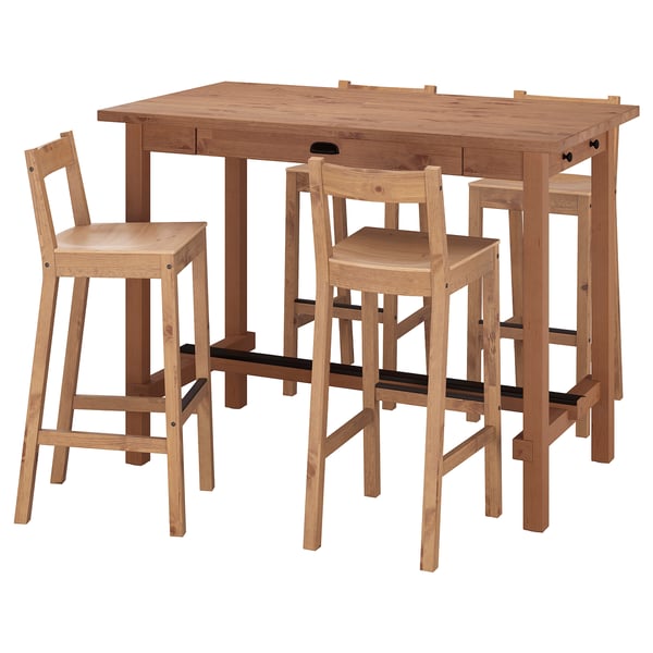 A light brown wooden bar set with table and stools. The table has drawers and the stools have backrests, made of solid pine.