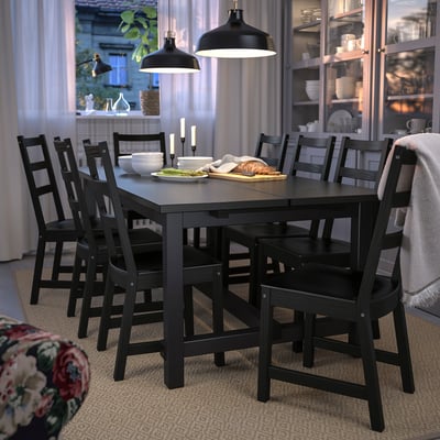Modern black dining set with extendable table and ladderback chairs. Soft pendant lighting, dishware in glass cabinet.