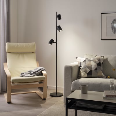 Modern living room with black floor lamp, rocking chair, sofa, and coffee table.