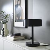 NYMÅNE black lamp on white cabinet with books and plant.