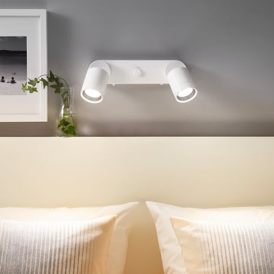 NYMÅNE dual spotlight on gray wall above bed, adjustable, with decor.