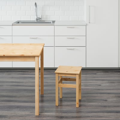 Wooden kitchen stool next to table and sink.