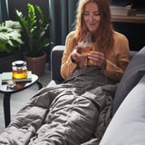 Woman relaxes on couch, tea blanket labeled ODONVIDE.