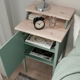 Bedside table with open and closed storage, displaying books, clock, and glass, showcasing practical and stylish design.