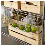 Metal shelf holds wooden crates and wire baskets. Green limes sit in wire basket under wooden crate.