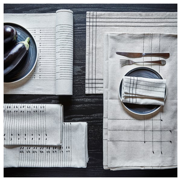 Two place settings with OMBONAD white and gray napkins, plates, knife, fork, and bowl on a black textured surface.