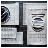 Two place settings with OMBONAD white and gray napkins, plates, knife, fork, and bowl on a black textured surface.